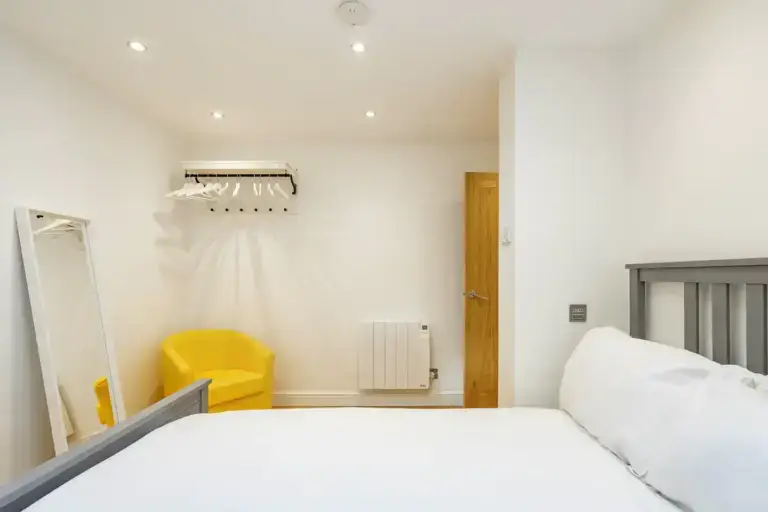 Double bedroom with a yellow armchair and coat hooks