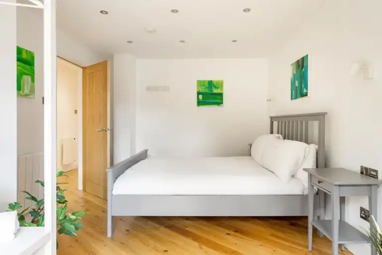 Double bedroom with wooden flooring and a doorway to the terrace