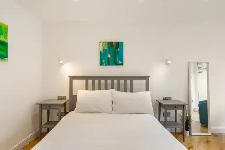 Double bed beneath colourful framed artwork