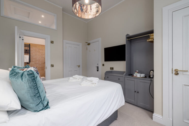 Double bed beside grey fitted cupboards and a window seat