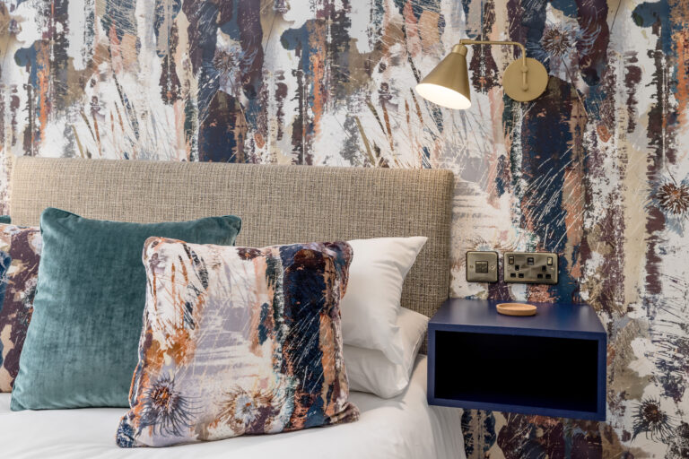 Patterned cushions against an abstract bedroom feature wall