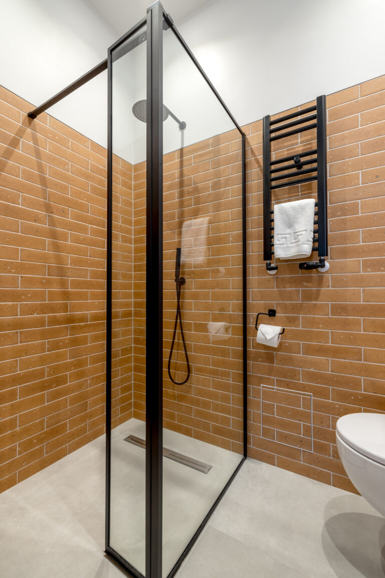 Black-framed glass shower enclosure with ochre tiles