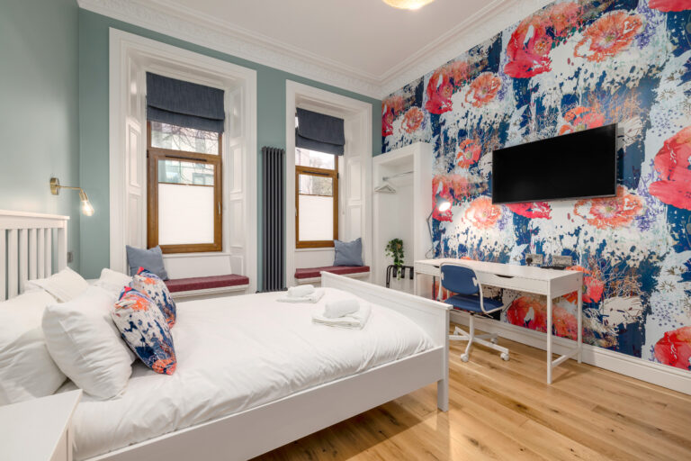 Studio bedroom with tall windows and a wall-mounted television