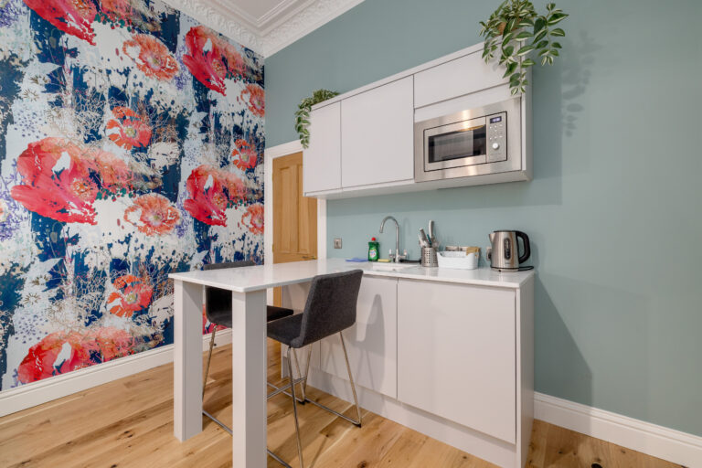 Studio kitchenette beside a bold floral feature wall