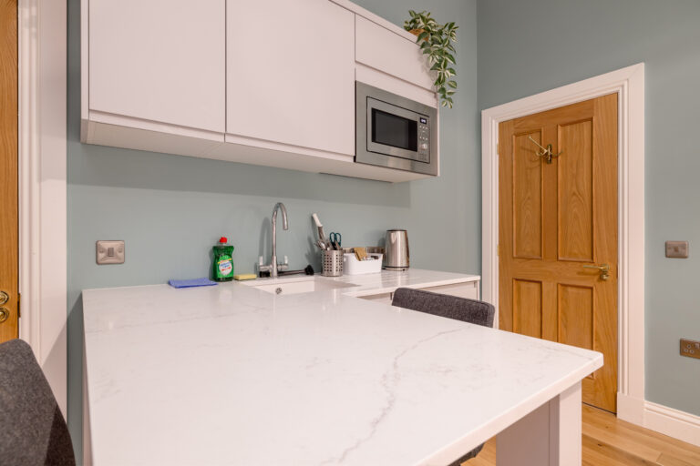 White studio kitchenette with a microwave and breakfast counter