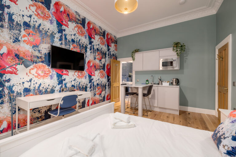 Studio room with a double bed, kitchenette and colourful floral wall