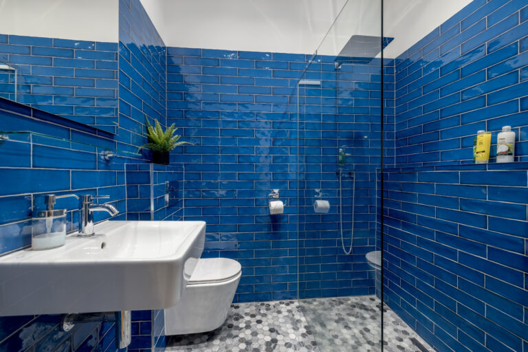 Blue-tiled bathroom with a basin, toilet and glass shower