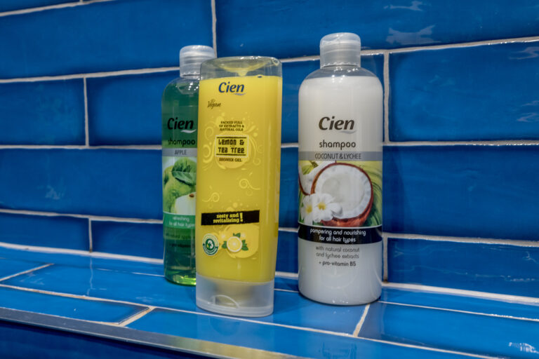 Toiletries displayed on a blue-tiled shower shelf