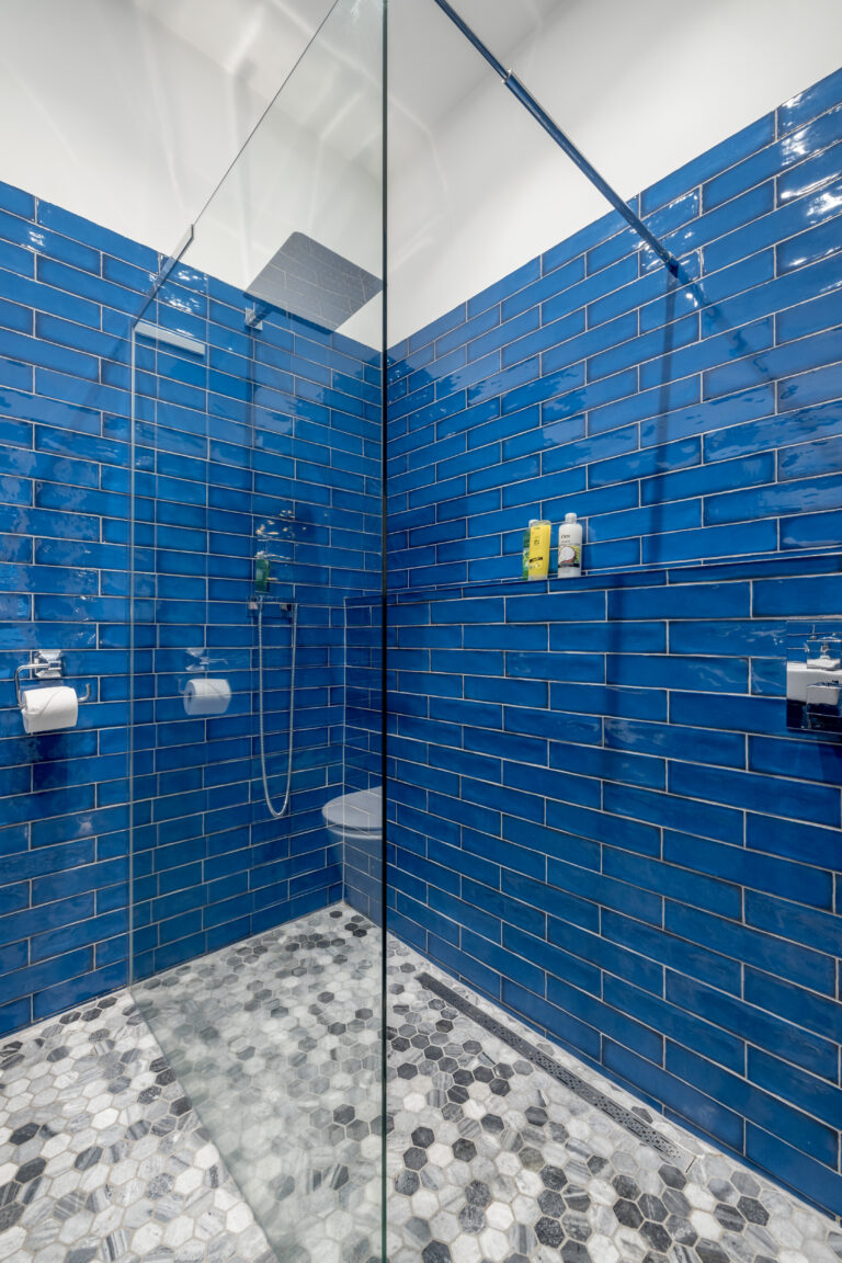 Glass shower enclosure with blue tiled walls