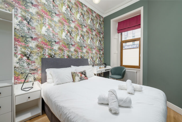 Double bed and green armchair beside a floral feature wall