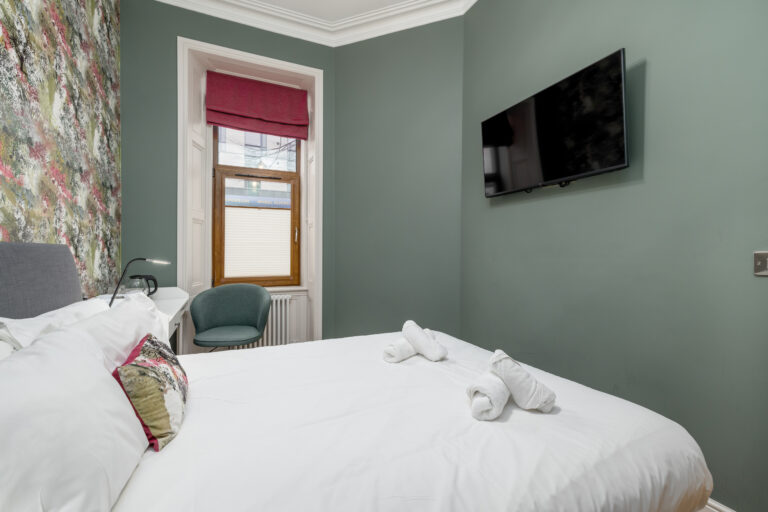 Double bedroom with a wall-mounted television and tall window