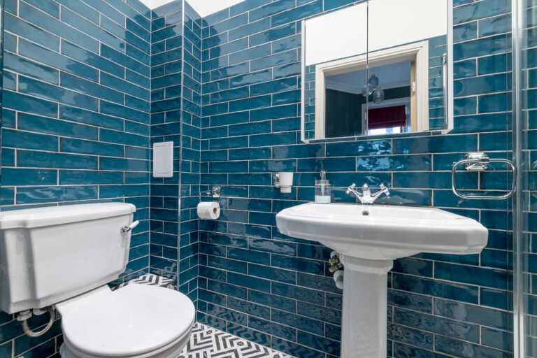 Teal-tiled bathroom with a basin, toilet and shower