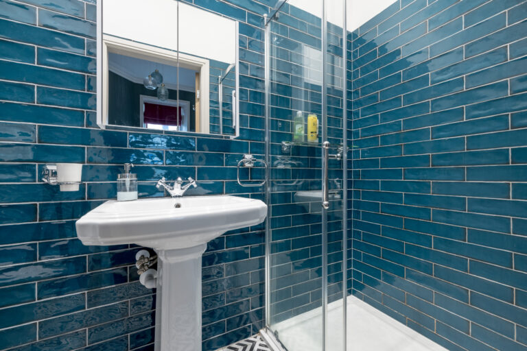White basin and mirror against teal bathroom tiles