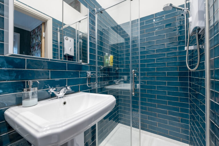 Teal-tiled shower room with a basin and glass enclosure