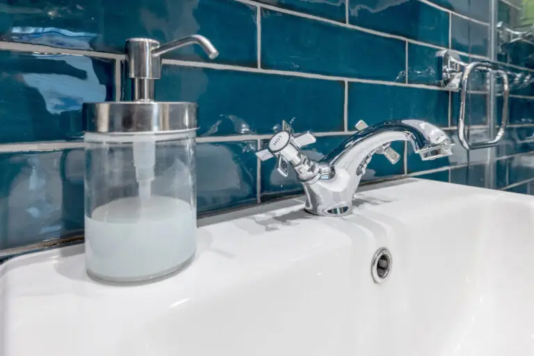 Bathroom basin and soap dispenser against teal tiles