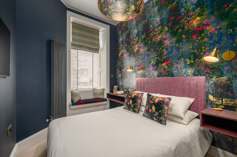 Double bedroom with floral wallpaper and a cushioned window seat