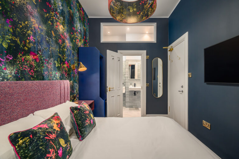 Bedroom with a pink headboard and colourful floral wallpaper