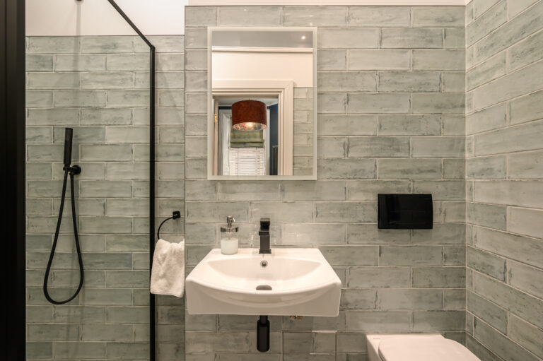 Bathroom basin and mirror beside a grey-tiled shower