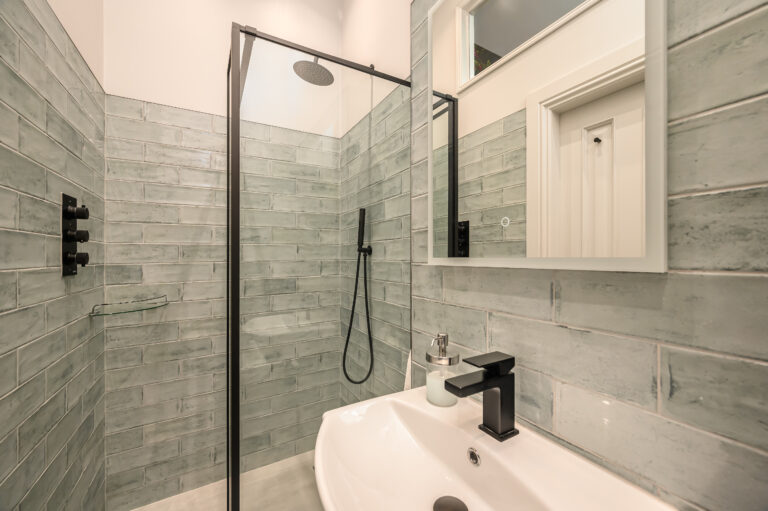 Grey-tiled shower room with a glass enclosure and basin