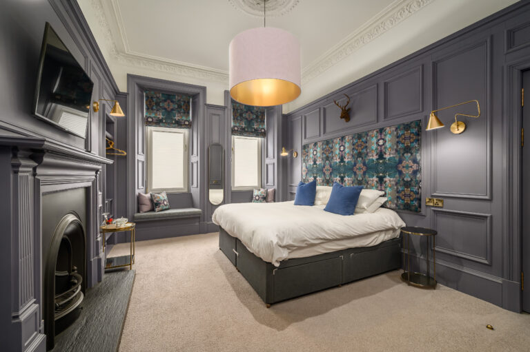 Guest bedroom with grey panelling and an original fireplace