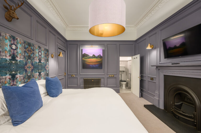 Bedroom with blue cushions, grey panelling and a fireplace
