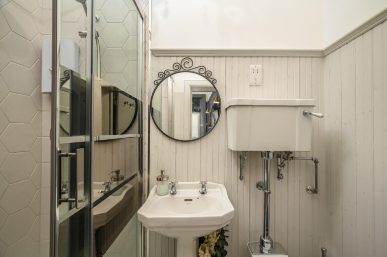 Bathroom basin and round mirror beside a glass shower enclosure