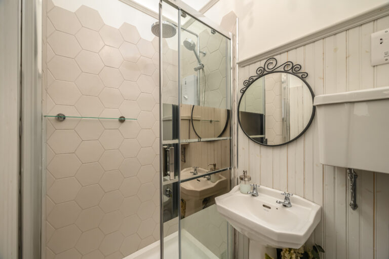En-suite bathroom with white panelling and a round mirror