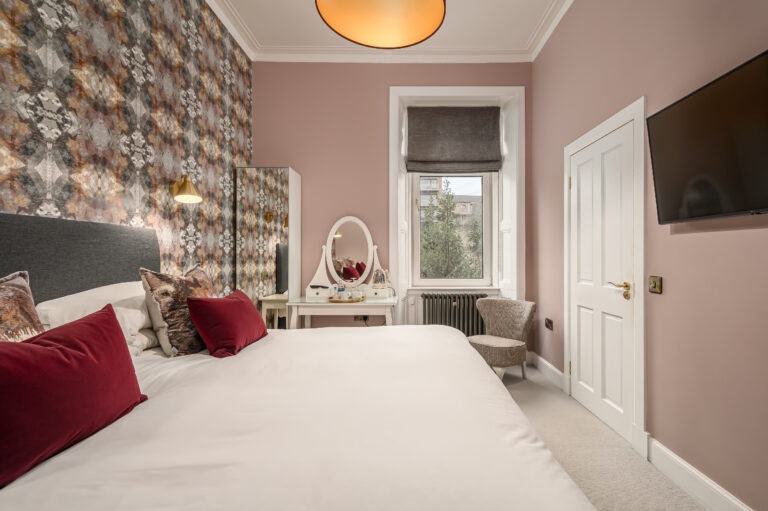 Twin beds beside a dressing table and tall window