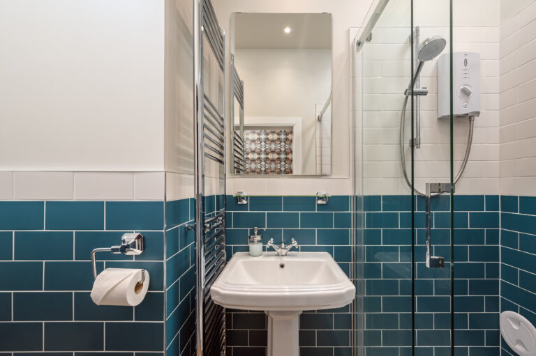 Teal-tiled shower room with a glass enclosure and mirror