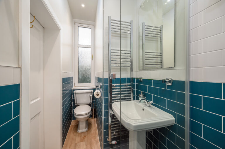 Narrow shower room with teal tiles and a pedestal basin