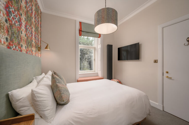 Double bed beside a window and wall-mounted television