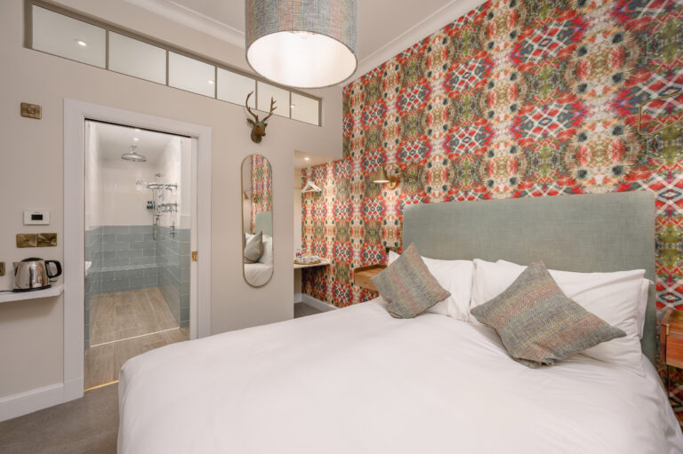 Double bedroom with patterned wallpaper and a grey headboard