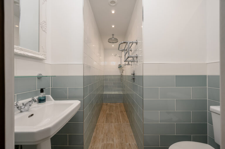 Long shower room with a glass enclosure and pale green tiles
