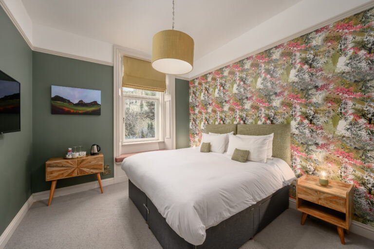 Twin bedroom with a yellow lampshade and framed landscape art