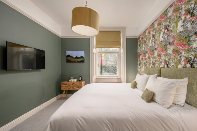 Twin beds beside a wooden cabinet and floral feature wall