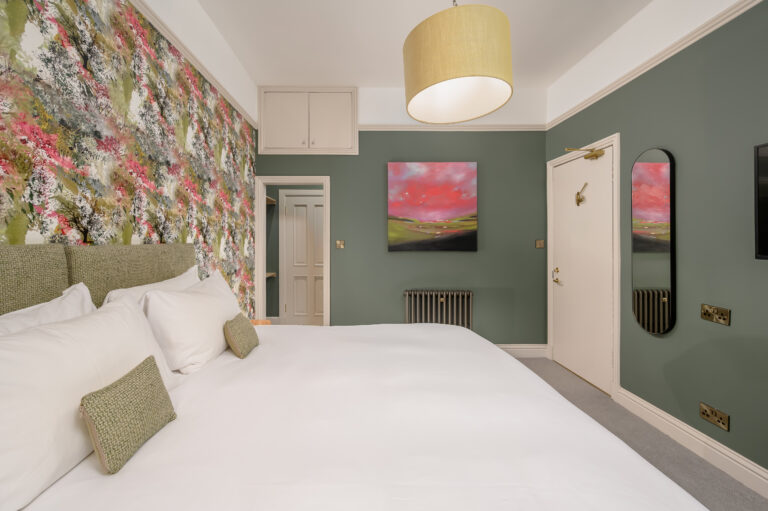Twin beds beside a floral feature wall in a green guest room