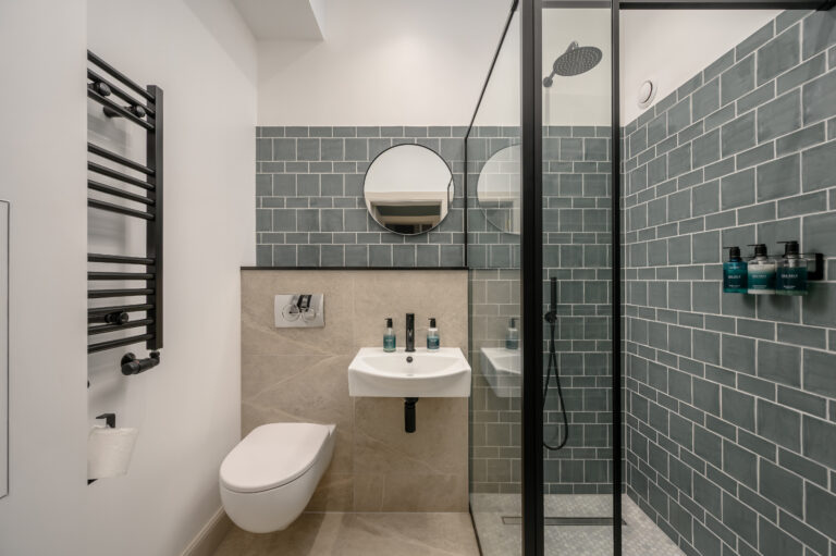 Grey-tiled bathroom with a shower, toilet and basin