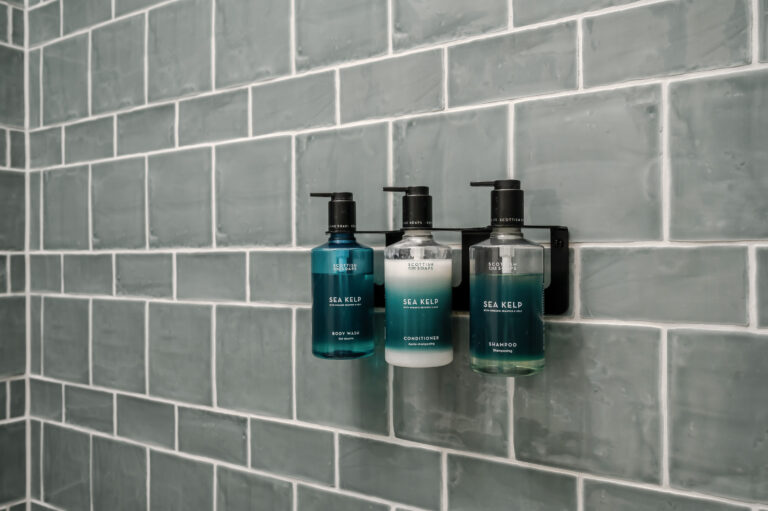 Shower toiletries on a shelf against grey tiles