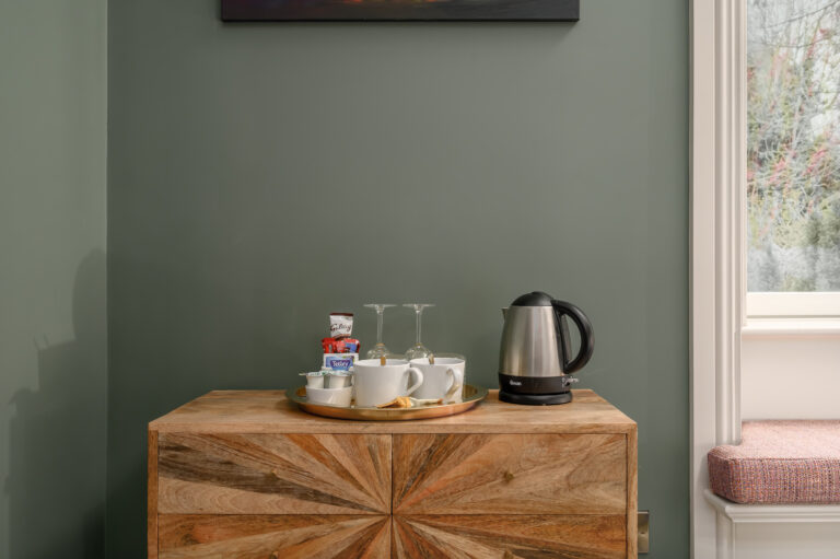 Tea tray and kettle on a wooden guest room cabinet