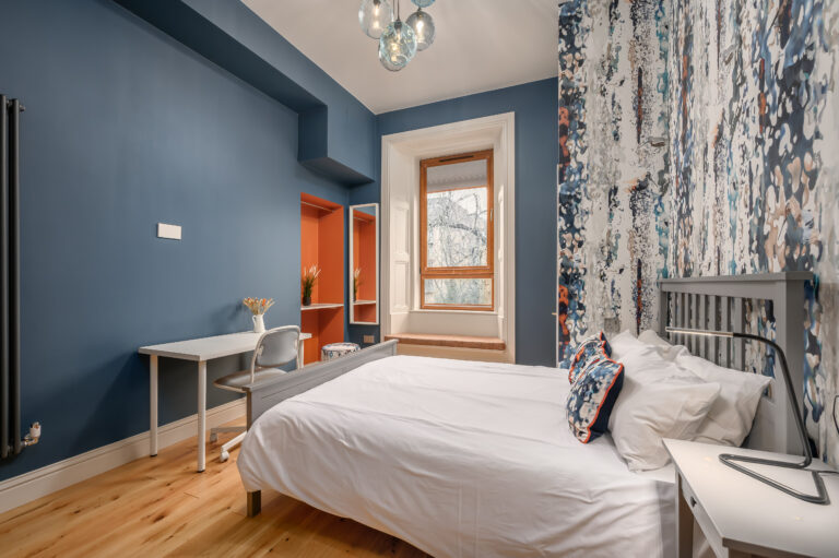 Blue-walled studio bedroom with kitchenette and patterned feature wall
