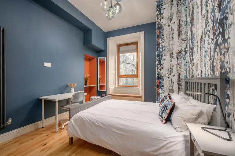 Blue-walled studio bedroom with kitchenette and patterned feature wall