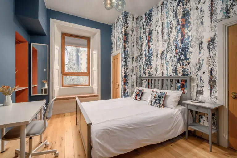 Studio bedroom with patterned cushions and a desk by the window