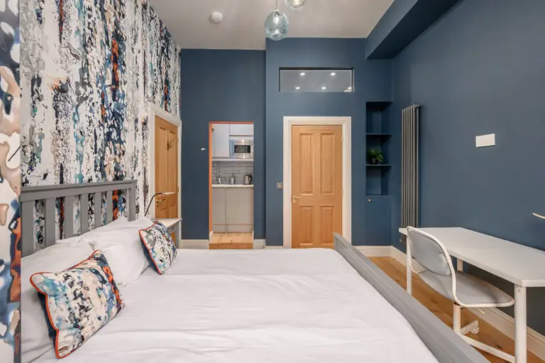 Double bed and desk in a blue-walled studio room
