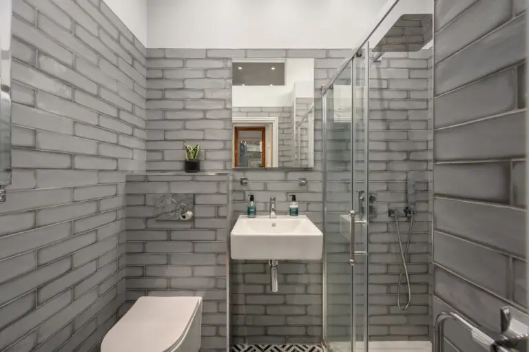 Compact grey-tiled bathroom with a glass shower enclosure