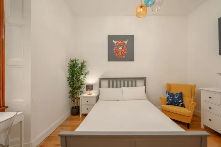 Double bedroom with framed animal artwork and a yellow chair