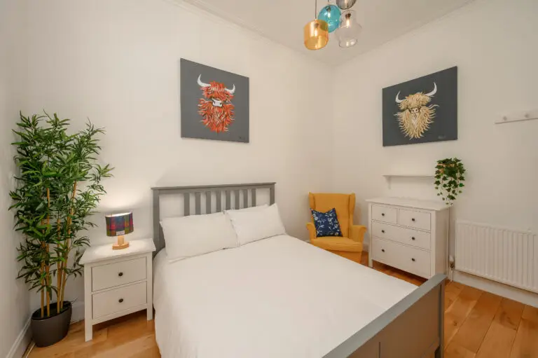 Double bed with a yellow armchair and potted plant