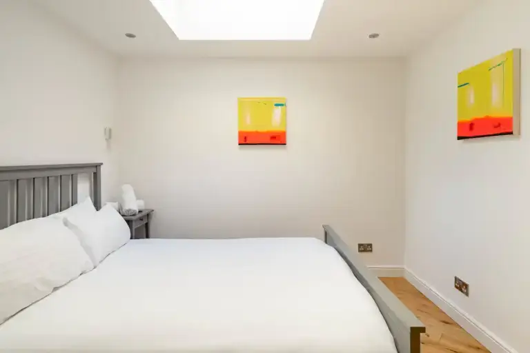 Double bedroom with grey headboard and colourful wall art
