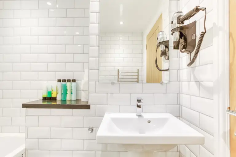 Bathroom basin and tiled wall with toiletries on a shelf