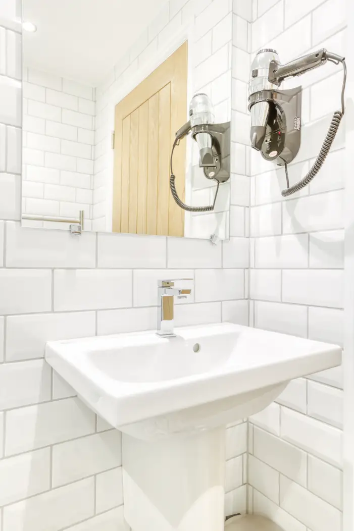 White bathroom basin beneath a mirror and wall lights