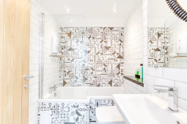 Bathroom with patterned tiles, a bath and a white basin